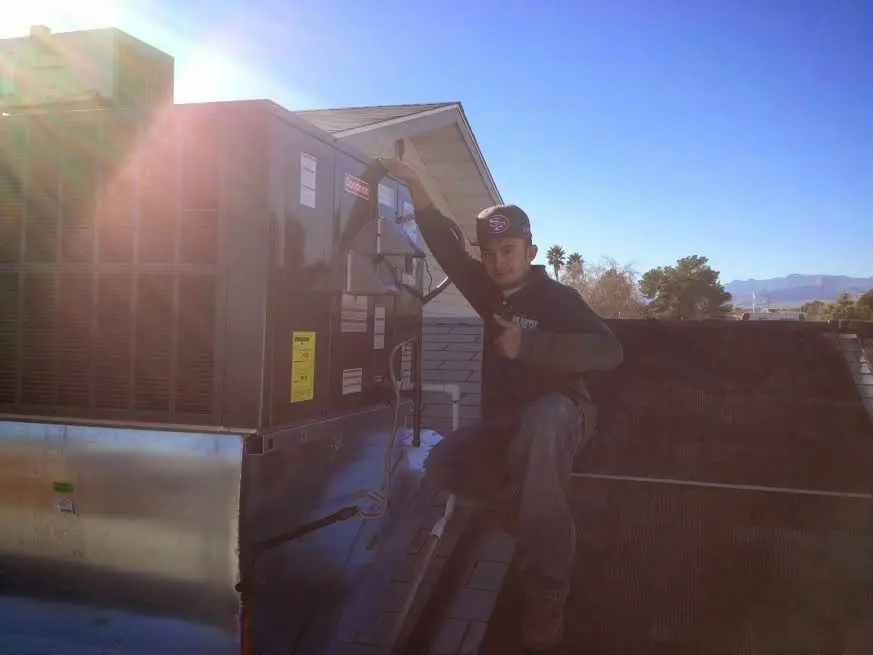 HVAC technician performing AC Tune-Up on a rooftop unit in Baker